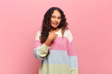 Genç İspanyol kadın mutlu, gururlu ve şaşırmış görünüyor, neşeli bir şekilde kendini gösteriyor, kendinden emin ve kibirli hissediyor.