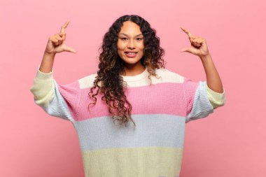 Genç İspanyol kadın kendi gülüşünü çiziyor ya da özetliyor, iki eliyle, olumlu ve mutlu görünüyor, sağIık kavramı