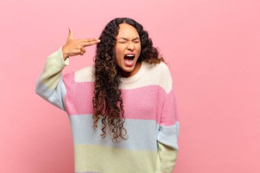 Genç İspanyol kadın mutsuz ve stresli görünüyor, intihar jesti elle silah işareti yapıyor, kafasını işaret ediyor.