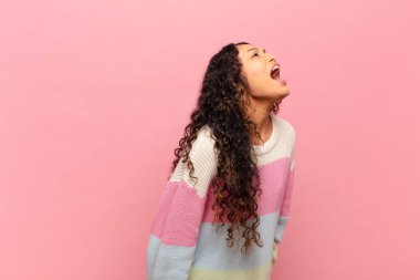 Genç İspanyol kadın öfkeyle bağırıyor, agresif bir şekilde bağırıyor, stresli ve kızgın görünüyor.