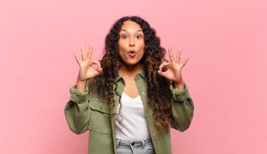 Genç İspanyol kadın şok olmuş, şaşırmış ve şaşırmış hissediyor. Onaylıyor. İki eliyle işaret veriyor.