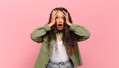 Genç İspanyol kadın hoş olmayan bir şekilde şok olmuş, korkmuş ya da endişeli görünüyor ağzı sonuna kadar açık ve iki kulağını da elleriyle kapatıyor.