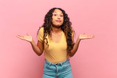 Genç İspanyol kadın şaşkın ve şaşkın hissediyor, doğru cevap veya karardan emin değil, bir seçim yapmaya çalışıyor.