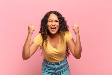 Genç İspanyol kadın mutlu, pozitif ve başarılı hissediyor, zaferi, başarıları veya iyi şansı kutluyor.