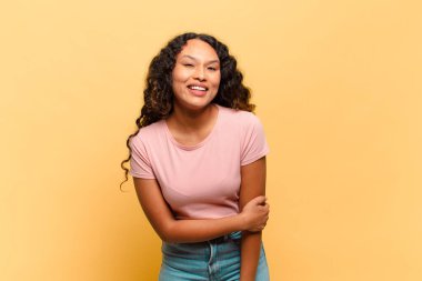 Genç İspanyol kadın utangaç ve neşeli bir şekilde gülüyor, arkadaş canlısı ve olumlu ama güvensiz bir tavırla.