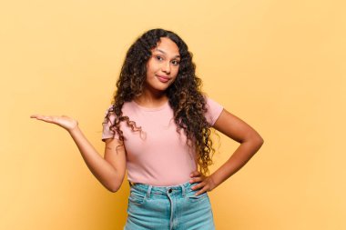 Genç İspanyol kadın gülümsüyor, kendinden emin, başarılı ve mutlu hissediyor, fotokopi alanında fikir veya konsept gösteriyor.