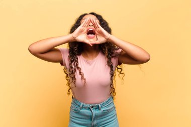 Genç İspanyol kadın mutlu, heyecanlı ve pozitif hissediyor. Elleri ağızda, bağırarak bağırıyor.