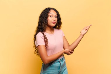 Genç İspanyol kadın gururla ve güvenle gülümsüyor, mutlu ve tatmin olmuş hissediyor ve fotokopi alanında bir konsept gösteriyor.