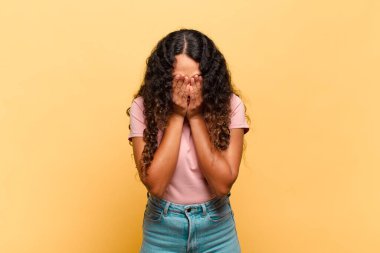 Genç İspanyol kadın üzgün, hayal kırıklığına uğramış, gergin ve depresif, iki eliyle yüzünü kaplayan, ağlayan