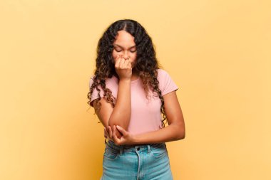 Genç İspanyol kadın kendini ciddi, düşünceli ve endişeli hissediyor. Eli çenesine değmiş şekilde yan yan bakıyor.