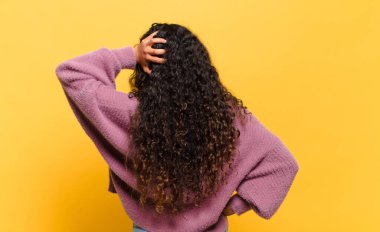 Genç İspanyol kadın düşünüyor ya da şüphe ediyor, kafasını kaşıyor, kafası karışık ve kafası karışık, arkaya ya da arkaya bakıyor.