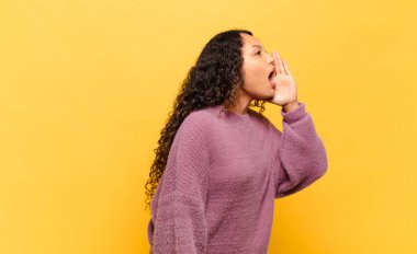 Genç İspanyol kadın profil görüşü, mutlu ve heyecanlı görünüyor, bağırıyor ve kenardaki boşluğu kopyalamak için arıyor