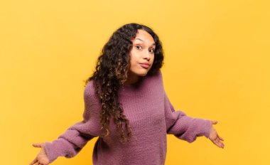 young hispanic woman feeling clueless and confused, having no idea, absolutely puzzled with a dumb or foolish look