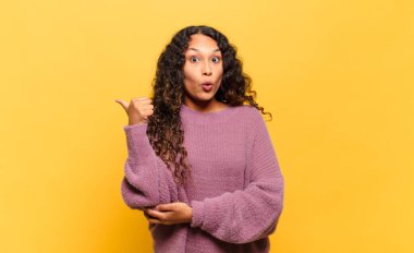 Genç İspanyol kadın inançsızlıktan şaşkın şaşkın bakıyor, yan taraftaki objeyi işaret ediyor ve diyor ki: