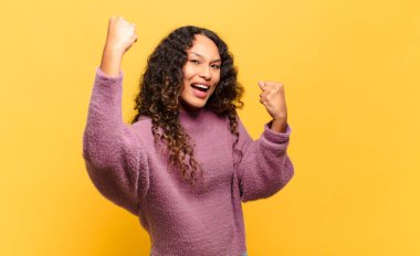 Genç İspanyol kadın muzaffer bir şekilde bağırıyor. Heyecanlı, mutlu ve şaşırmış görünüyor. Kutlama yapıyor.