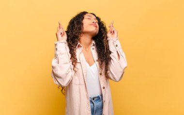 Genç İspanyol kadın endişeyle dua ediyor ve endişeli bakışlarıyla iyi şanslar diliyor.