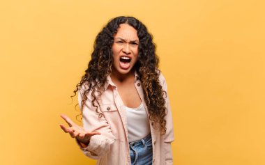 young hispanic woman looking angry, annoyed and frustrated screaming wtf 