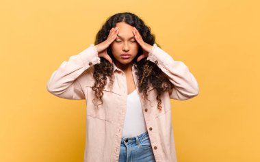 Genç İspanyol kadın stresli ve hayal kırıklığına uğramış görünüyor. Baskı altında, baş ağrısı ve sorunlarıyla çalışıyor.