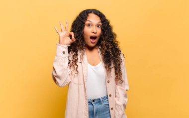 Genç İspanyol kadın kendini başarılı ve tatmin olmuş hissediyor, ağzı açık gülümsüyor, elle imza atıyor.