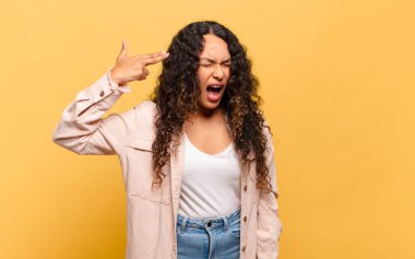 Genç İspanyol kadın mutsuz ve stresli görünüyor, intihar jesti elle silah işareti yapıyor, kafasını işaret ediyor.