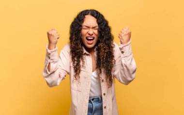 Genç İspanyol kadın mutlu, şaşırmış ve gururlu hissediyor, bağırıyor ve başarıyı büyük bir gülümsemeyle kutluyor.