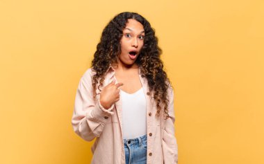 Şok olmuş ve ağzı açık, kendini işaret eden genç İspanyol bir kadın.