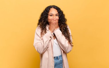 Genç İspanyol kadın mutlu ve heyecanlı, şaşırmış ve şaşırmış elleriyle ağzını kapatmış, tatlı bir ifadeyle kıkırdıyor.