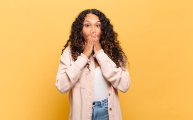 Genç İspanyol kadın endişeli, üzgün ve korkmuş hissediyor, elleriyle ağzını kapatıyor, endişeli ve berbat görünüyor.