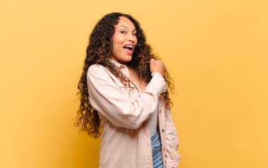 Genç İspanyol kadın mutlu, pozitif ve başarılı hissediyor, meydan okumayla karşılaştığında motive oluyor veya iyi sonuçları kutluyor.