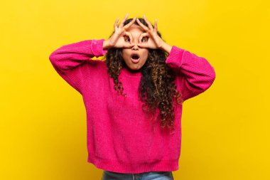 Genç İspanyol kadın şaşkın, şaşkın ve şaşırmış hissediyor, elinde şaşkın, inançsız bir bakışla gözlük tutuyor.