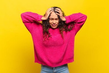 Genç İspanyol kadın kendini stresli ve hayal kırıklığına uğramış hissediyor. El ele tutuşuyor. Yorgun, mutsuz ve migren ağrısı çekiyor.