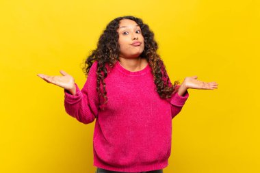 Genç İspanyol kadın şaşkın ve şaşkın hissediyor, doğru cevap veya karardan emin değil, bir seçim yapmaya çalışıyor.