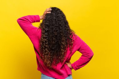 Genç İspanyol kadın bilgisiz ve şaşkın hissediyor, bir çözüm düşünüyor, eli kalçasında, diğeri kafasında, dikiz aynasından.