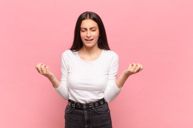 Genç, güzel bir kadın sinirli, sinirli, kızgın bakışlar ve sıkı yumruklar ile agresif bir şekilde bağırıyor.