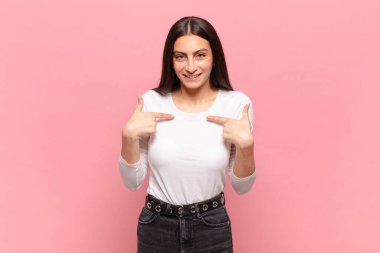 Genç, güzel bir kadın mutlu, şaşırmış ve gururlu hissediyor. Heyecanlı ve şaşkın bir bakışla kendini işaret ediyor.