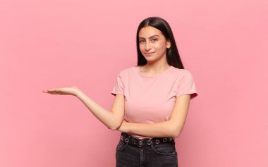 Genç, güzel bir kadın neşeyle gülümsüyor, mutlu hissediyor ve fotokopi alanında bir konsept gösteriyor.