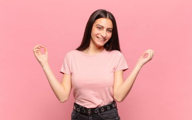 Genç ve güzel bir kadın son derece mutlu ve şaşırmış görünüyor, başarıyı kutluyor, bağırıyor ve zıplıyor.