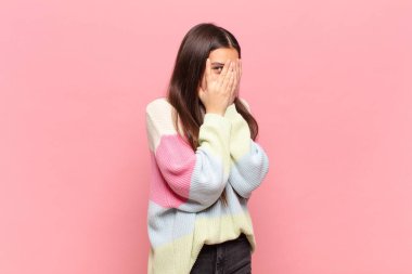 Genç, güzel bir kadın korkmuş ya da utanmış hissediyor. Gözleri yarı kapalı ya da ellerle dikizliyor.