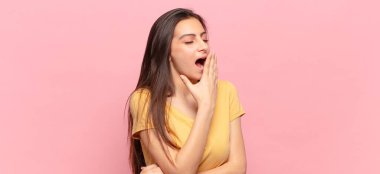 Genç ve güzel bir kadın sabahın erken saatlerinde uykulu, yorgun ve sıkkın bir şekilde esniyor.