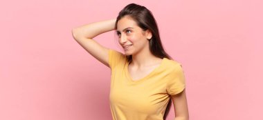 Genç, güzel bir kadın neşeli ve sıradan bir şekilde gülümsüyor, olumlu, mutlu ve kendinden emin bir bakışla göğüs göğüse tutuşuyor.