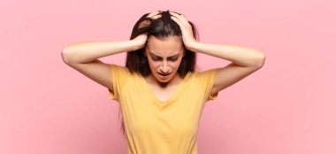 Genç ve güzel bir kadın stresli ve hayal kırıklığına uğramış hissediyor, elele tutuşuyor, yorgun, mutsuz ve migren ağrısı çekiyor.