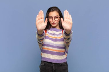 Genç ve güzel bir kadın ciddi, mutsuz, kızgın ve hoşnutsuz görünüyor. Ya da her iki avucunun içinde de dur diyor. öğrenci konsepti