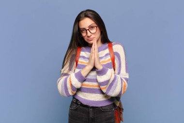 Genç, güzel bir kadın endişeli, umutlu ve dindar hissediyor. Avuçlarına bastırılmış, af dileyen sadık bir şekilde dua ediyor. öğrenci konsepti