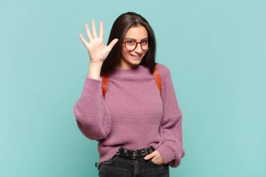 Genç ve güzel bir bayan gülümsüyor ve arkadaş canlısı görünüyor. Beş ya da beş numarayı gösteriyor. Elleri önde ve geri sayıyor. öğrenci konsepti