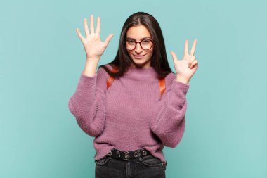 Genç, güzel bir kadın gülümsüyor ve arkadaş canlısı görünüyor. Sekiz ya da sekiz numarayı gösteriyor. Elleri önde ve geri sayıyor. öğrenci konsepti