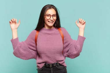 Genç ve güzel bir kadın son derece mutlu ve şaşırmış görünüyor, başarıyı kutluyor, bağırıyor ve zıplıyor. öğrenci konsepti