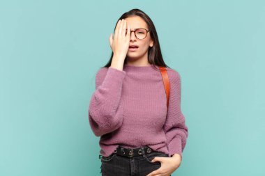 Genç ve güzel bir kadın uykulu, sıkılmış ve esniyor, baş ağrısı ve yüzünün yarısını kaplayan bir eliyle. öğrenci konsepti