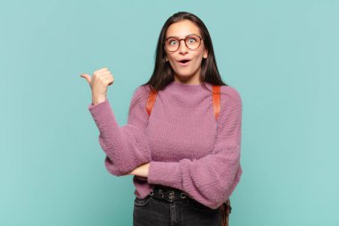 Genç ve güzel bir kadın inançsızlıktan şaşkın şaşkın bakıyor, yan taraftaki objeyi işaret ediyor ve 