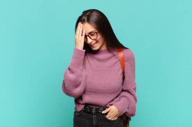 Genç ve güzel bir kadın gülüyor ve alnına şaplak atıyor. Unuttum ya da aptalca bir hataydı. öğrenci konsepti 