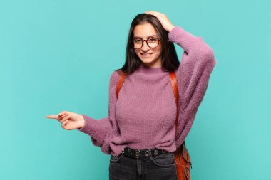 Genç, güzel bir kadın gülüyor, mutlu, pozitif ve şaşırmış görünüyor, yanal fotokopi alanını işaret eden harika bir fikrin farkına varıyor. öğrenci konsepti